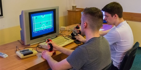 Powiększ grafikę: Dwóch wychowanków przy pomocy joysticków rozgrywa mecz na starym komputerze.