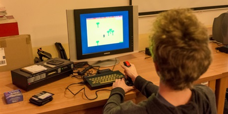 Powiększ grafikę: Wychowanek przy pomocy joysticka gra w grę na starym komputerze.