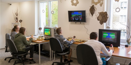 Powiększ grafikę: Na zdjęciu czterech wychowanków siedzi przed telewizorami i gra na retrokomputerach C64, Zx Spectrum i Timex 2048 w gry: River Raid, Bomb Jack i Grand Prix