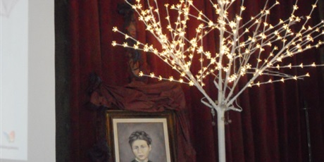 Powiększ grafikę: Scena na której znajduje się obraz Ireny Sendlerowej oraz świecące drzewko symbolizujące jabłoń pod która Irena Sendlerowa ukrywała słoik z nazwiskami i imionami dzieci.