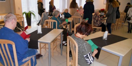 Powiększ grafikę: Na zdjęciu seniorzy przy stolikach oglądają kartki świąteczne otrzymane od wychowanków z Bursy Gdańskiej