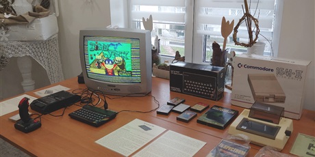 Powiększ grafikę: Na zdjęciu stół, na którym znajduje się komputer ZX Spectrum, magnetoforn Unitra i stary telewizor. Obok leżą kasety magnetofonowe z grami, drukarka Seikosha i kartony po komputerze i stacji dyskietek