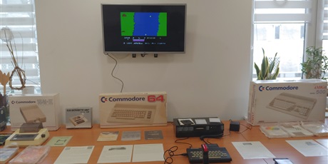 Powiększ grafikę: Na zdjęciu stół, na którym znajduje się komputer TC2048 i stacja dysków FDD3000. Obok leżą kartony po komputerach, drukarka Seikosha oraz dyskietki z grami.