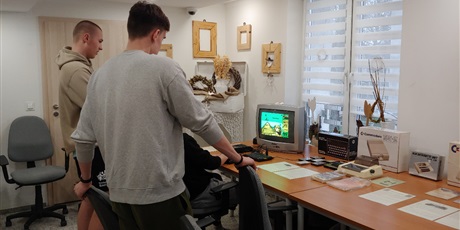 Powiększ grafikę: Na zdjęciu wychowanek grający na komputerze ZX Spectrum w grę”Bomb Jack”. Za nim stoi dwójka wychowanków oglądających grę.