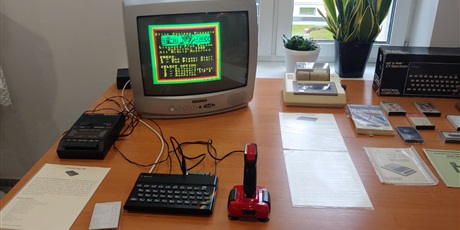 Powiększ grafikę: Na zdjęciu widać stolik, na którym jest komputer ZX Spectrum 48 z magnetofonem i drukarką podłączony do małego telewizora