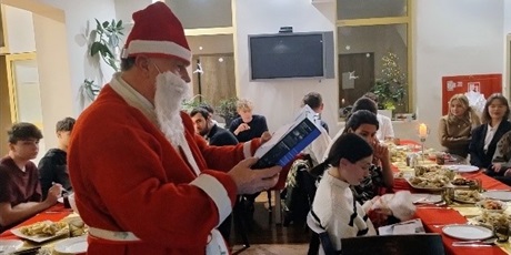 Powiększ grafikę: Na zdjęciu święty Mikołaj w oddali wychowankowie siedzący przy stole