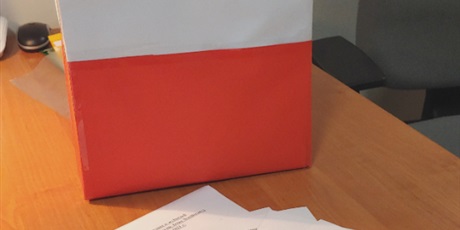 Powiększ grafikę: Na zdjęciu znajduje się urna do głosowania w barwach polskiej flagi oraz listy i karty do głosowania.