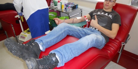 Powiększ grafikę: Wychowanek leży na czerwonym fotelu. Zdjęcie wykonane w trakcie pobierania krwi