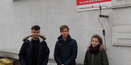 Powiększ grafikę: Na zdjęciu trzech wychowanków stojących przed budynkiem Regionalnego Centrum Krwiodawstwa i Krwiolecznictwa w Gdańsku