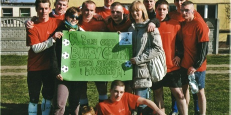 Powiększ grafikę: Drużyna Bursy Gdańskiej w czerwonych koszulkach wraz dziewczętami z plakatem z hasłem „W Bolku grają Bursy Gdańskie, Do bramki strzelają i wygrywają”