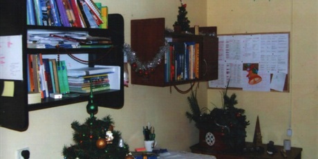 Powiększ grafikę: Mała, udekorowana choinka stoi na biurku wychowanków, na ścianie znajdują się lampki świąteczne. 