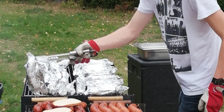 Powiększ grafikę: Wychowanek układa jedzenie na grillu.