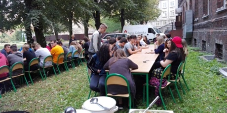 Powiększ grafikę: Młodzież siedzi przy stołach ustawionych na terenie za budynkiem Podwala Staromiejskiego.