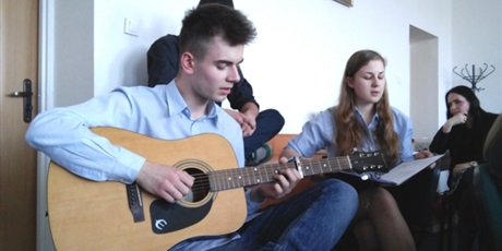 Powiększ grafikę: Wychowanek gra na gitarze, przygląda mu się wychowawczyni i wychowanka.
