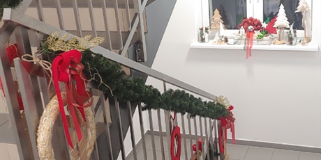 Powiększ grafikę: Na zdjęciu widać poręcze schodowe na półpiętrze w bursie ze świątecznym wystrojem. W tle widać okno, na parapecie którego stoją stroiki świąteczne.