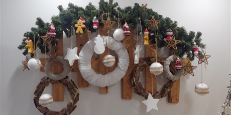 Powiększ grafikę: Na zdjęciu widać zawieszone na ścianie ozdoby świąteczne, nieduże gwiazdki, bombki i mikołajki.
