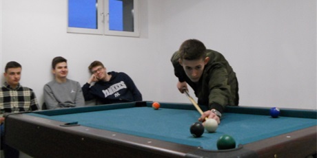 Powiększ grafikę: Na zdjęciu trzech wychowanków w sali sportowej oglądających jak ich koledzy grają w bilarda