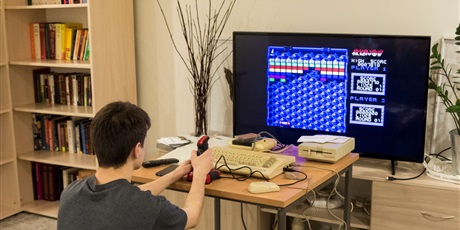 Powiększ grafikę: Na zdjęciu wychowanek siedzący przed telewizorem i grający na retrokomputerze C64 w grę Arkanoid