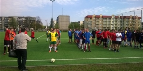 Powiększ grafikę: Na zielonym boisku w kolejno ustawionych rzędach stoi pięć drużyn. Pierwsza z nich ma na sobie czerwone stroje, druga zielono żółte, trzecia niebieskie, czwarta czerwone a piąta czarno niebieskie.