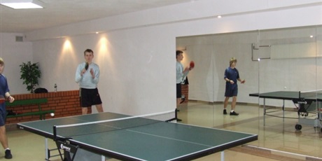 Powiększ grafikę: Chłopcy grają  mecz debla tenisa stołowego.