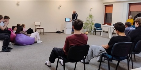 Powiększ grafikę: Młodzież siedząca na krzesłach oraz pufach słuchająca wykładu