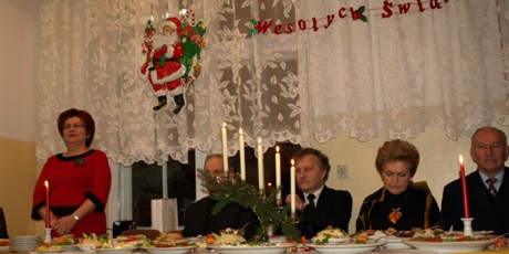 Powiększ grafikę: Udekorowany świątecznie stół w budynku przy ul. Lastadia. Za nim zasiadają goście,  obok nich stoi i przemawia Wicedyrektor Danuta Główczewska.