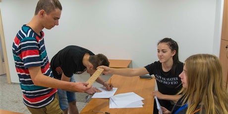 Powiększ grafikę: Na zdjęciu wychowanek stojący przed komisja wyborczą, która wręcza mu zakładkę do książki w ramach akcji „Gdańsk bez plastiku”. Obok inny wychowanek podpisuje się na liście do głosowania.