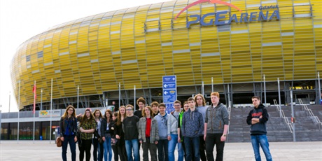 Powiększ grafikę: Siedemnaścioro wychowanków pozuje na tle budynku PGE Arena.