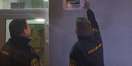 Powiększ grafikę: Zaprzyjaźnieni funkcjonariusze Straży Miejskiej wskazują tablicę z nazwą placówki